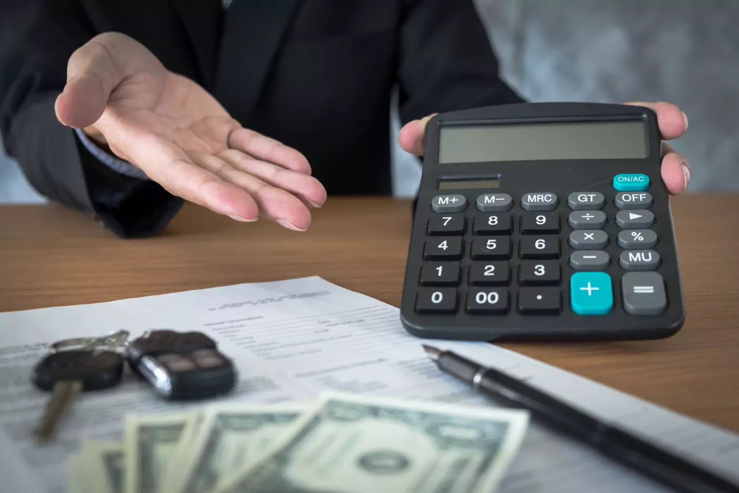 A man in black coat is holding a calculator and calculating a car loan